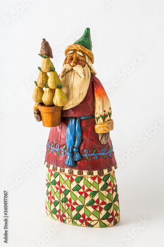 a styalized Santa Claus figurine  holding a pear tree and a partiidge, on an isolated white background. photo