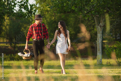 Walking down. Caucasian young and happy couple enjoying weekend together in the park on summer day. Look lovely, happy, cheerful. Concept of love, relationship, wellness, lifestyle. Sincere emotions.