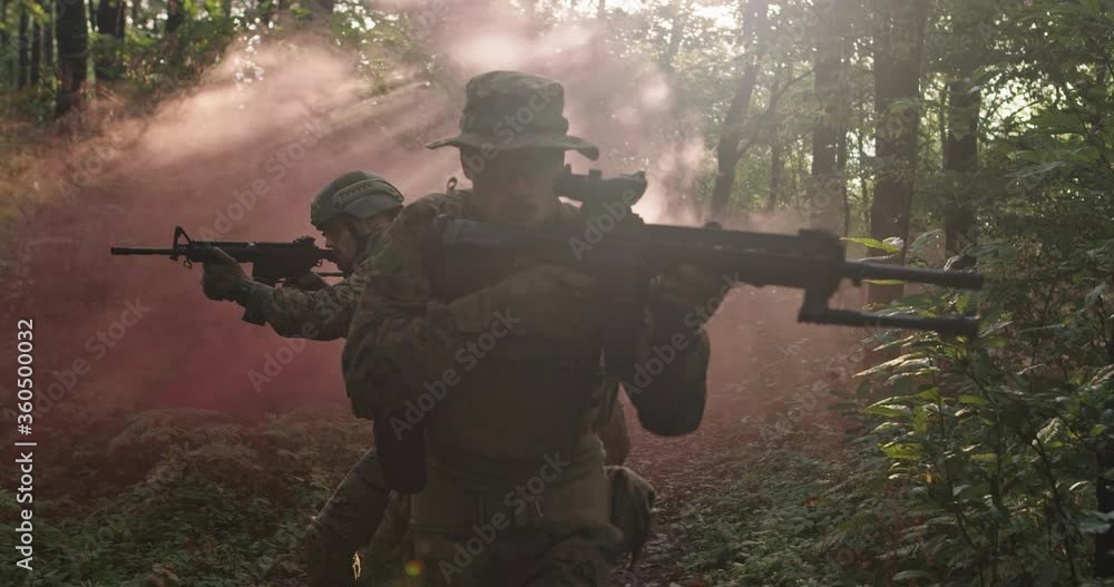 Soldiers in the smoke moving in battle operation through dense forest Soldiers in the smoke moving in battle operation through dense forest