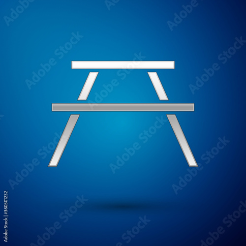 Silver Picnic table with benches on either side of the table icon isolated on blue background. Vector Illustration.
