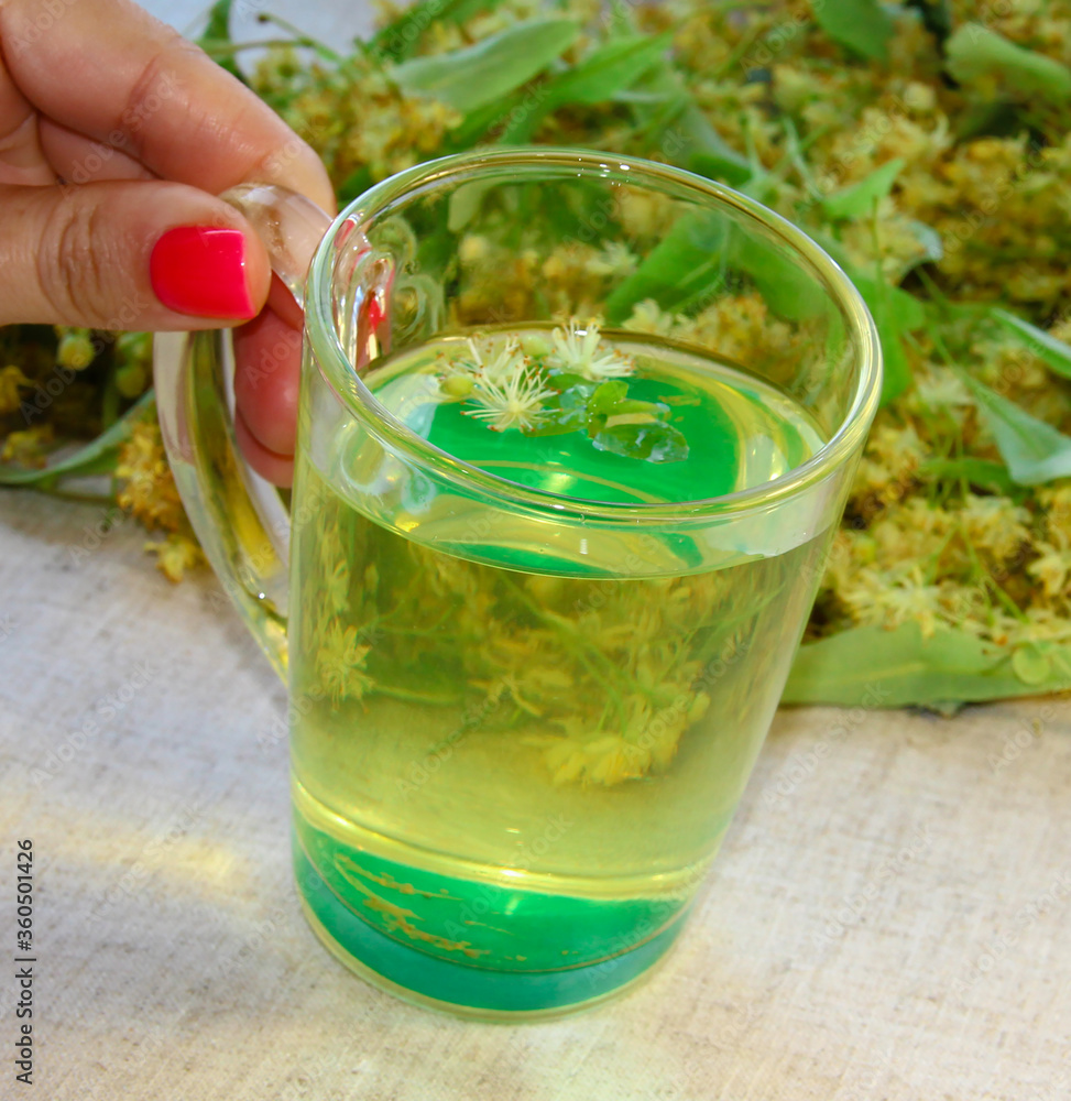 Lime tea in women's hands on the background of a linen tablecloth. Lime tea in women's hands on the background of a linen tablecloth.