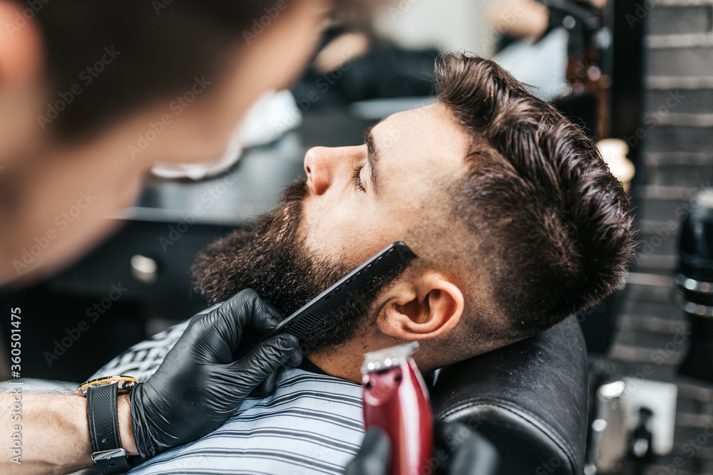 Fotka „Young good looking man visiting barber shop. Trendy and stylish  beard styling and cut.“ ze služby Stock | Adobe Stock