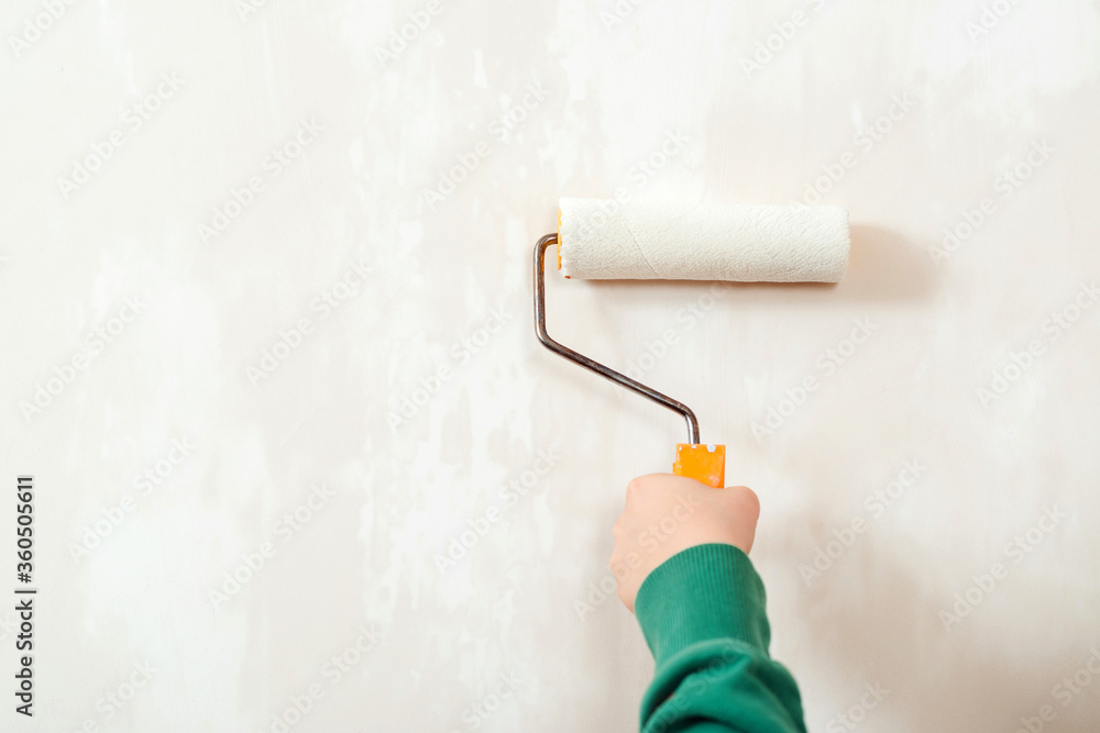 Obraz premium Worker paint wall by the rollers brush. Banner, copy space for text. Hand holding rollerb brush. Boy painting wall in room.