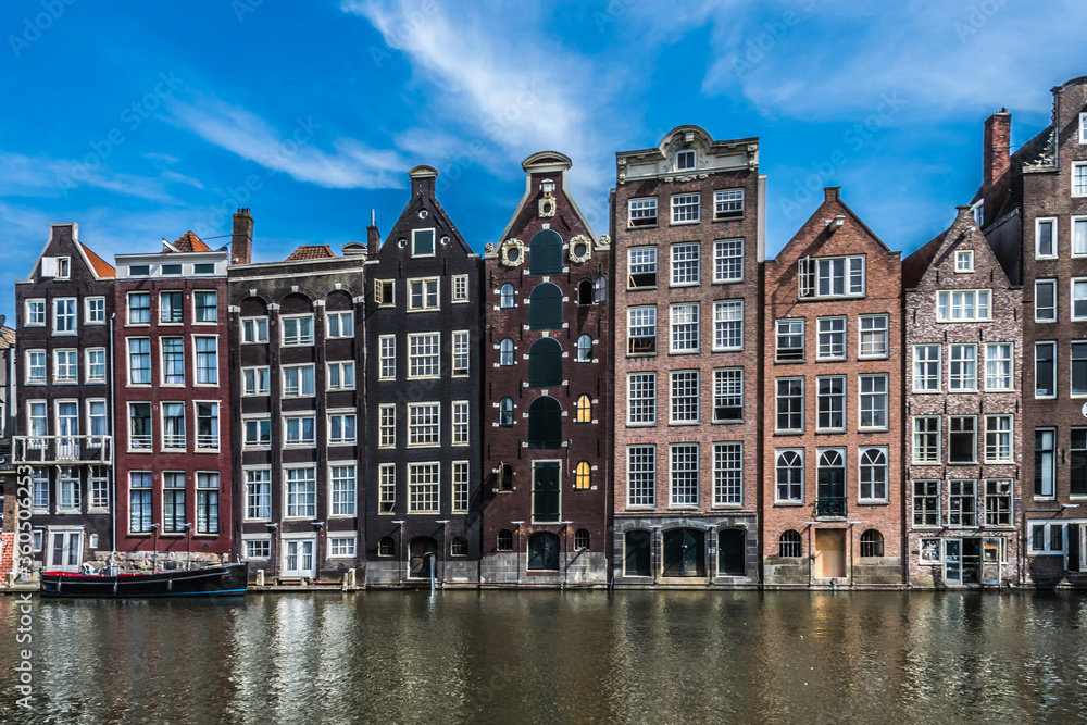 Old canal border houses in typical Dutch architectural style along a main canal in Amsterdam, North Holland, the Netherlands