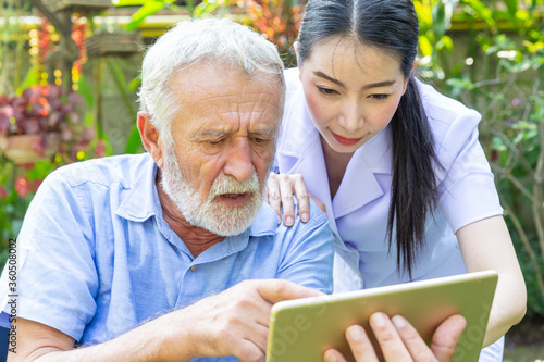 Nurse help senior retirement man working with laptop in backyard at home
