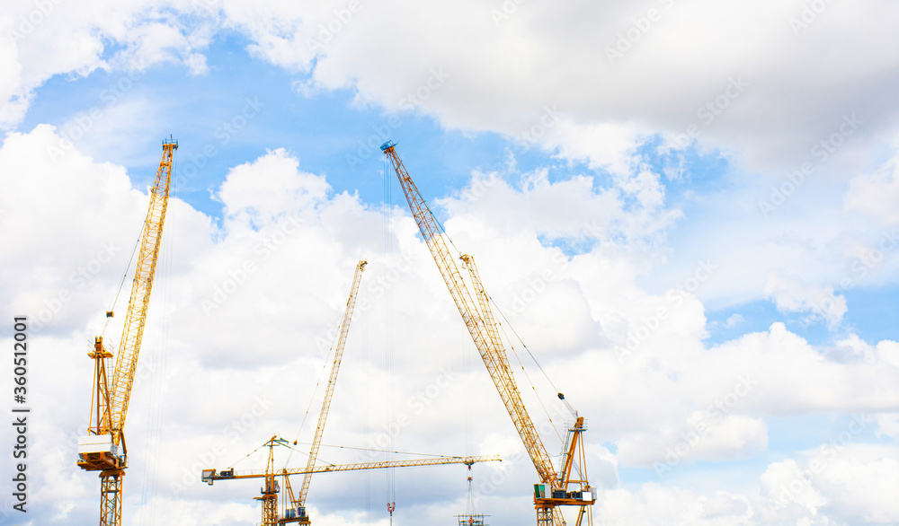 Panorama of crane construction site on background of blue sky and cloud.