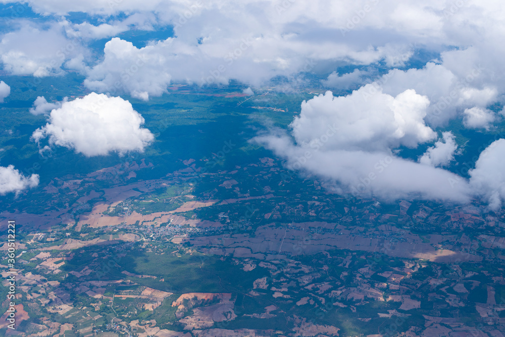 View from airplane on ground with fields, clouds,forest and rivers