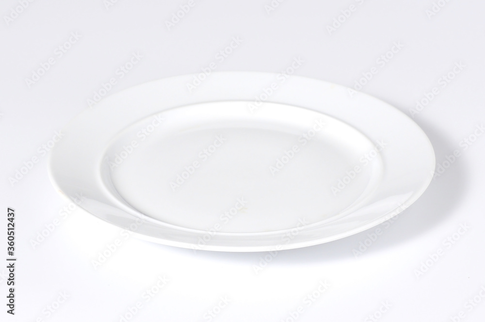An empty white enamel plate placed on a white background An empty white enamel plate placed on a white background