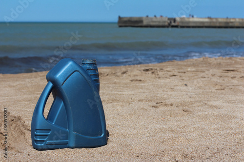 Blue plastic canister of motor oil on the beach.