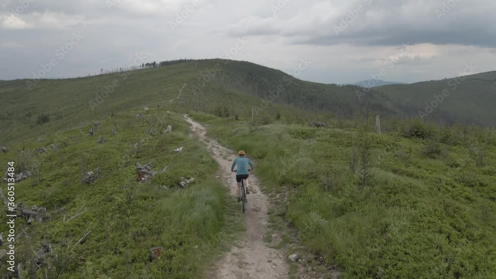 Aerial shot of mountainbike woman riding on bike in summer mountains landscape. Woman cycling MTB. Aerial shot of mountainbike woman riding on bike in summer mountains landscape. Woman cycling MTB.