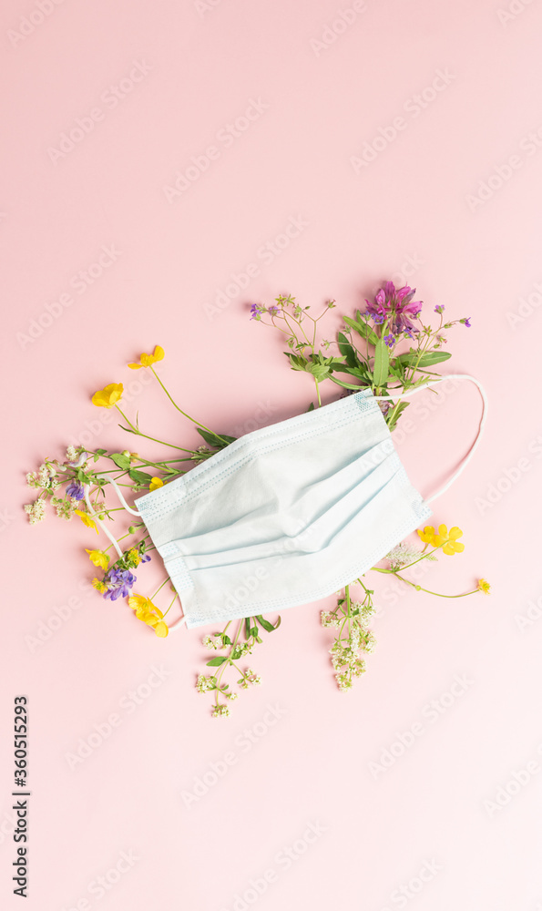 Protective medical mask and fresh flowers on a pink background. Flat layout place for text your design concept health Protective medical mask and fresh flowers on a pink background. Flat layout place for text your design concept health