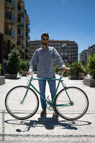 Outdoor portrait of handsome young man with fixed gear bicycle in the street