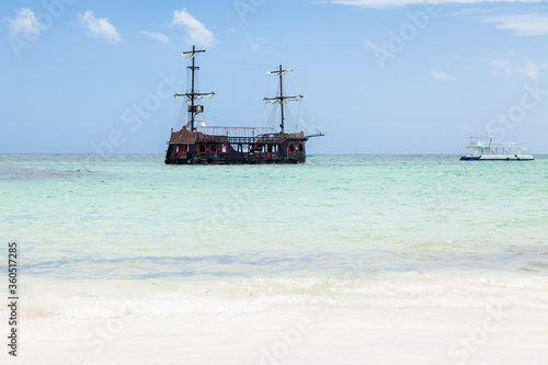 Wooden pirate ship boat made in vintage style sailing in waters of caribbean sea coast and atlantic ocean landscape of Dominican republic, Punta Cana