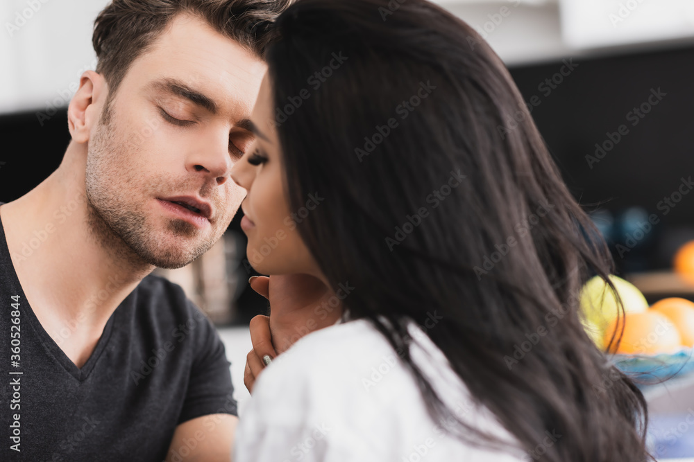 Selective focus of handsome man touching beautiful girlfriend in kitchen Selective focus of handsome man touching beautiful girlfriend in kitchen