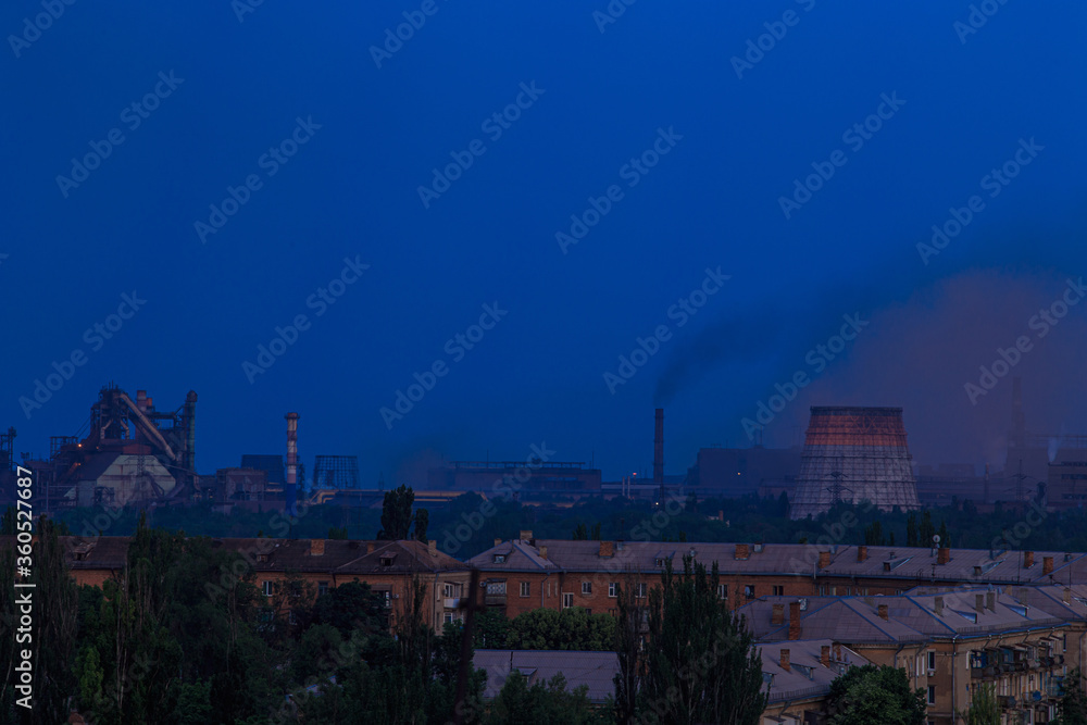 Evening in the city with a large metallurgical plant on the outskirts Evening in the city with a large metallurgical plant on the outskirts