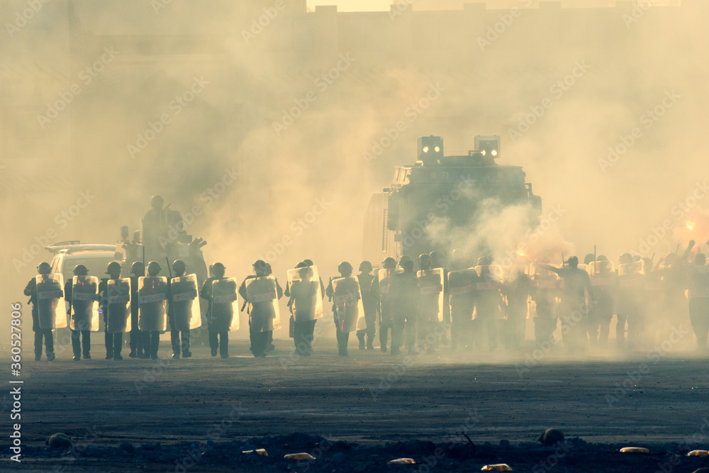 Military police riot response to a protest with tear gas, smoke, fire, explosions. Political expression, riot, protest, demostration and military concept. - obrazy, fototapety, plakaty 