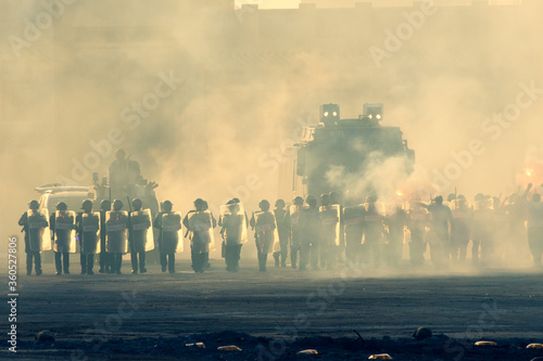 Military police riot response to a protest with tear gas, smoke, fire, explosions. Political expression, riot, protest, demostration and military concept. photo