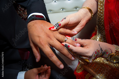 A bride is wearing a ring on the groom s finger. Indian Wedding.