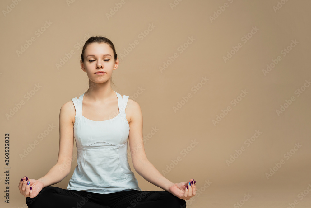 A girl sits in a lotus position and meditates with her eyes closed. Zen practice, breath technique. Consideration and praying A girl sits in a lotus position and meditates with her eyes closed. Zen practice, breath technique. Consideration and praying