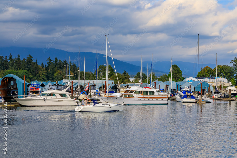 Boats docked at Coal Harbor in Vancouver Canada with Stanley Park and Grouse Mountain in the background