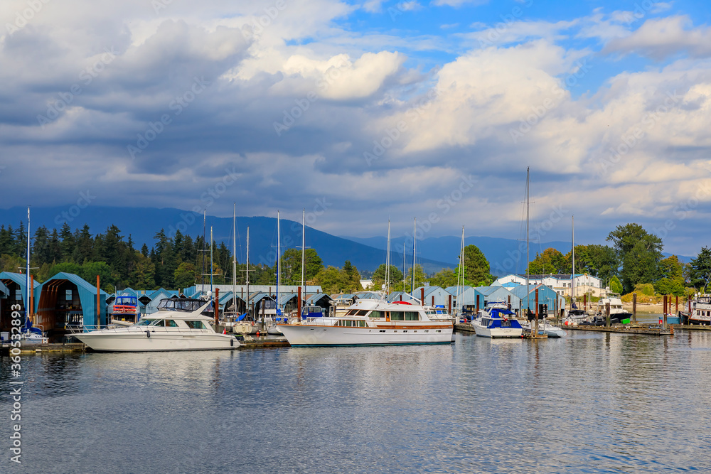 Boats docked at Coal Harbor in Vancouver Canada with Stanley Park and Grouse Mountain in the background