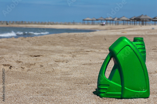 Colored plastic canister of motor oil on the beach. Green, Gold, Purple, Gray, Blue, Red, White.