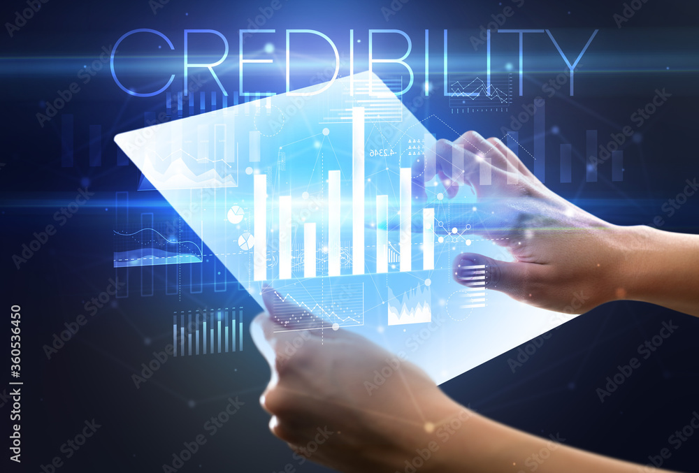 Hand holding futuristic tablet with CREDIBILITY inscription above, modern business concept Hand holding futuristic tablet with CREDIBILITY inscription above, modern business concept