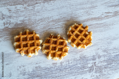Small round delicious soft belgian waffles on cutting board. Fresh belgian waffles with berries and caramel sauce top view. Copy space for text or mock up