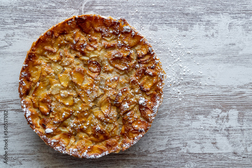 Obraz na płótnie Homemade baking. Freshly baked apple pie on a light wooden background sprinkled with icing sugar. w salonie