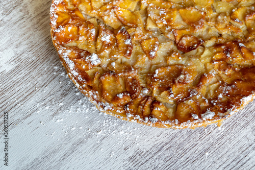 Obraz na płótnie Homemade baking. Freshly baked apple pie on a light wooden background sprinkled with icing sugar. w salonie