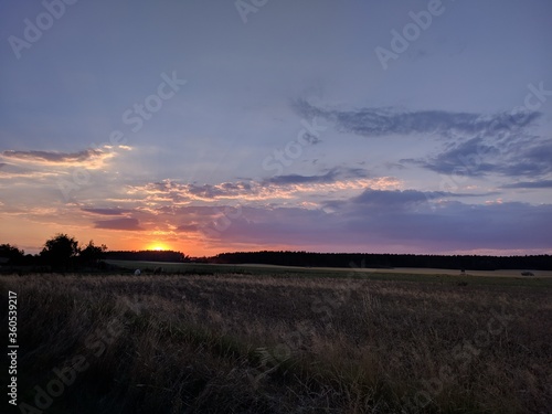 beautiful romantic orange sunset over the empty field with clouds in countryside