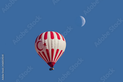 hot air balloon flying high below the moon in turkey  photo