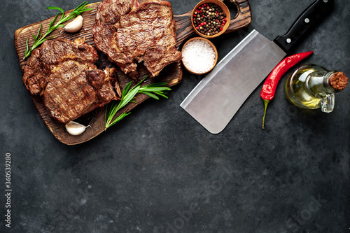 Two grilled beef steaks with spices on a stone background with copy space for your text.