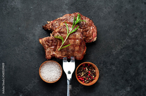 Grilled beef steak with spices on a meat fork on a stone background with copy space for your text.