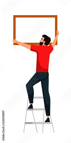 Man hanging picture frame on wall on white space