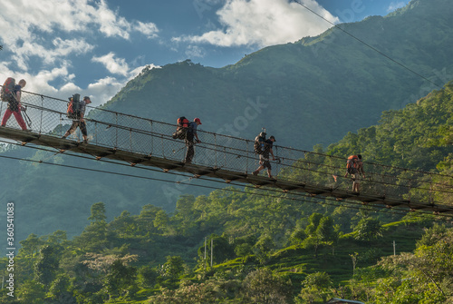 Konstfotografi At  the start of Annapurna Circuit trek, on trekking trail from Bhulbule village to Ngadi village, along Marshyangdi river - trekkers crossing the river on their way back from trek, Himalayas, Nepal