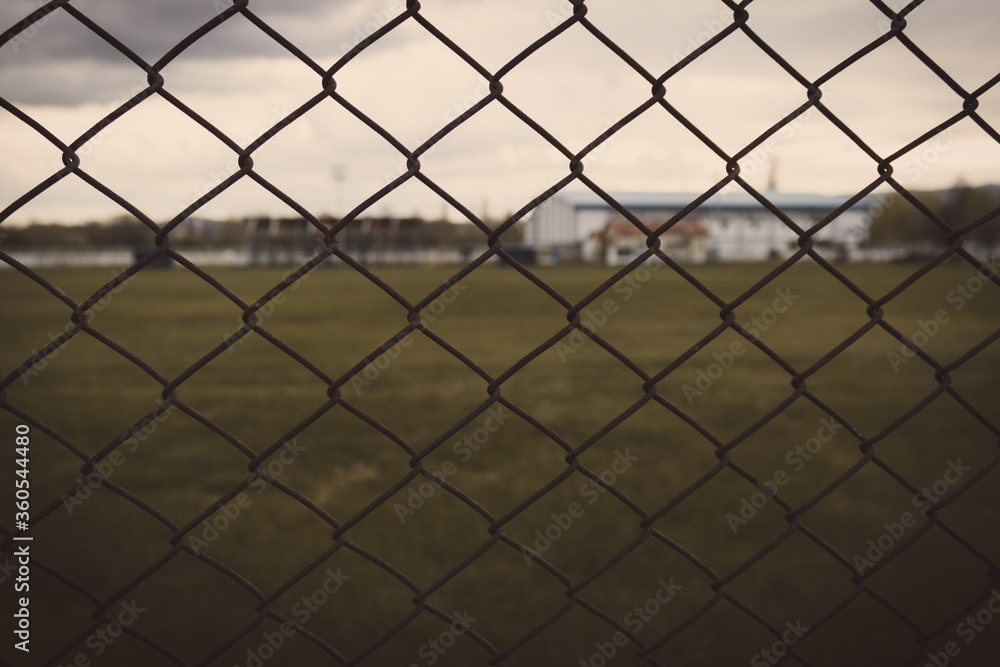 Chain link fence in farm with grassy field behind it. Cloudy sky and melancholic view. Chain link fence in farm with grassy field behind it. Cloudy sky and melancholic view.