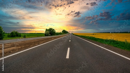 highway goes to the horizon between the fields of wheat