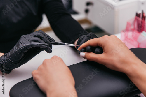 manicurist paints nails with a brush