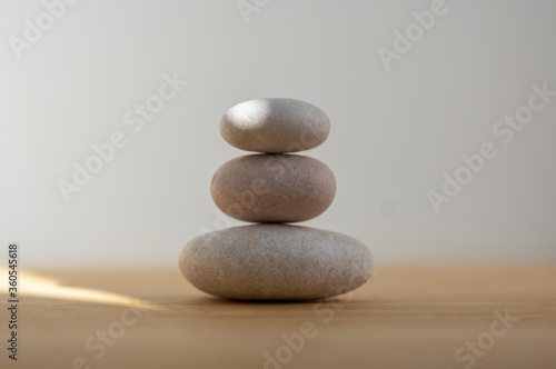 Stone cairn on striped grey white background  three stones tower  simple poise stones  simplicity harmony and balance 