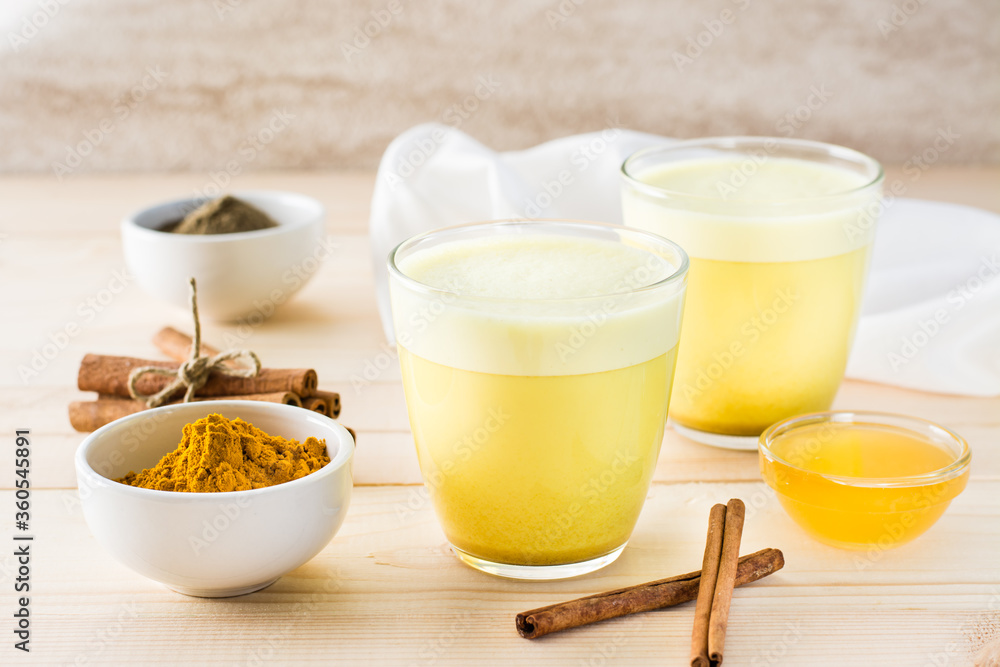 Detox drink. Golden milk with turmeric and cinnamon in glasses on a wooden table. Detox drink. Golden milk with turmeric and cinnamon in glasses on a wooden table.