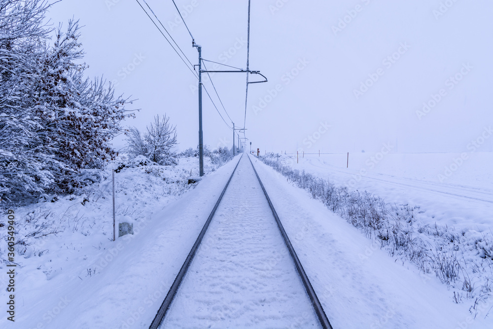 Snow covered train tracks leading into a thick fog. Straight railway tracks leading lines in wintertime