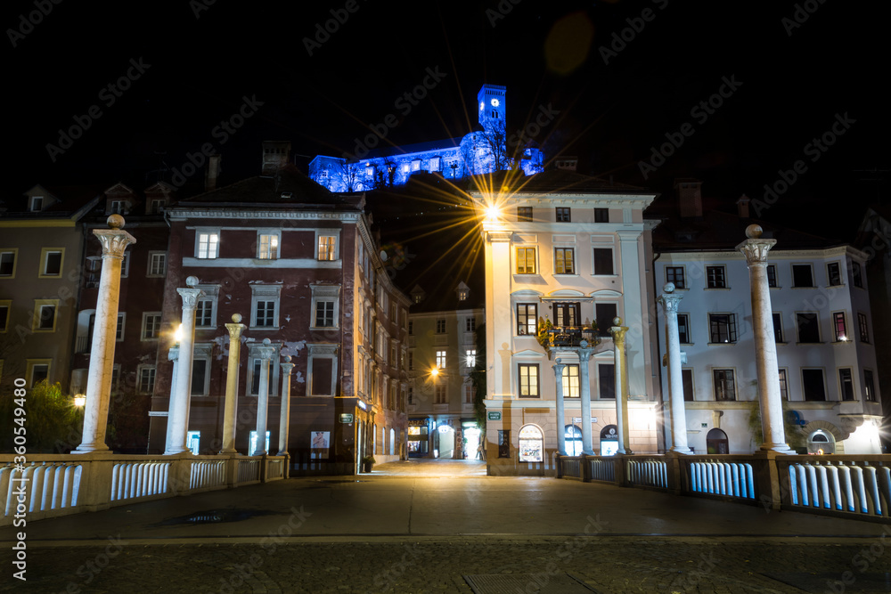 Ljubljana city at night. Capitol of Slovenia in December. Blue colors on castle walls. View of Cobblers bridge. Long exposure, wide shot, low angle