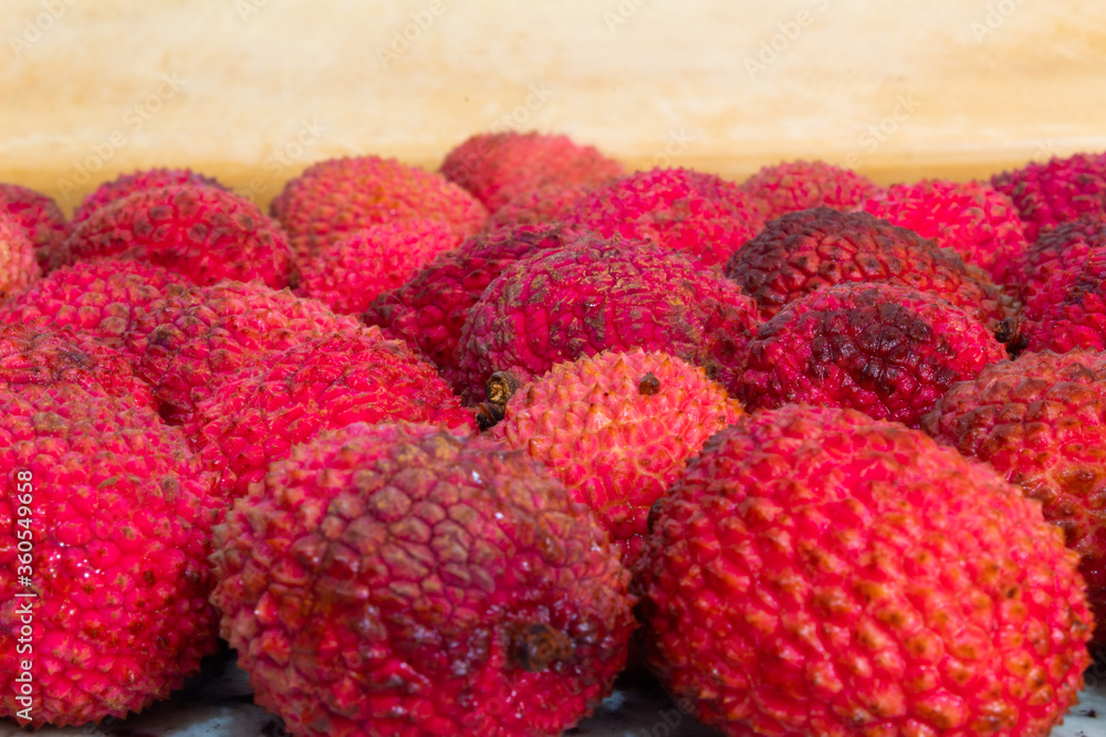 close up of many red lychees on a wooden colored background close up of many red lychees on a wooden colored background