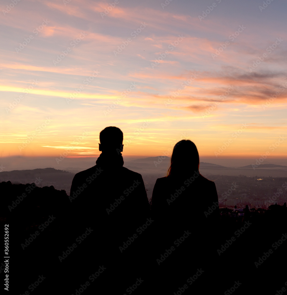 Couple silhouette looking to golden hour sky