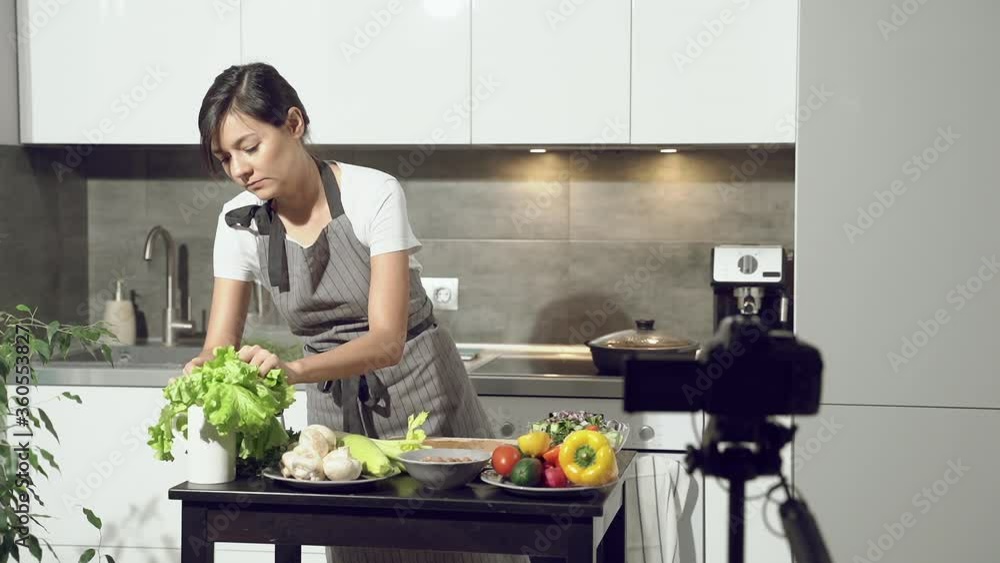 Attractive young woman recording a video about healthy eating on digital camera in the kitchen at home. Vlogging and social media concept. Attractive young woman recording a video about healthy eating on digital camera in the kitchen at home. Vlogging and social media concept.