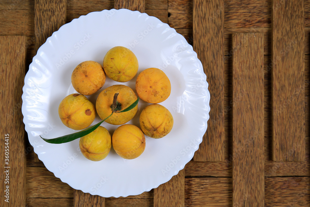 Fresh ripe tasty eggfruits in a white bowl isolated on wooden background