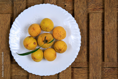 Wallpaper Mural Fresh ripe tasty eggfruits in a white bowl isolated on wooden background Torontodigital.ca