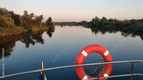 Lifesever on the boat. Panoramic river view. Calm water surface.