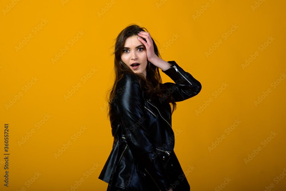 Excited young brunette female raising emotionally her hands while rejoicing about something, over yellow background in black wear Excited young brunette female raising emotionally her hands while rejoicing about something, over yellow background in black wear